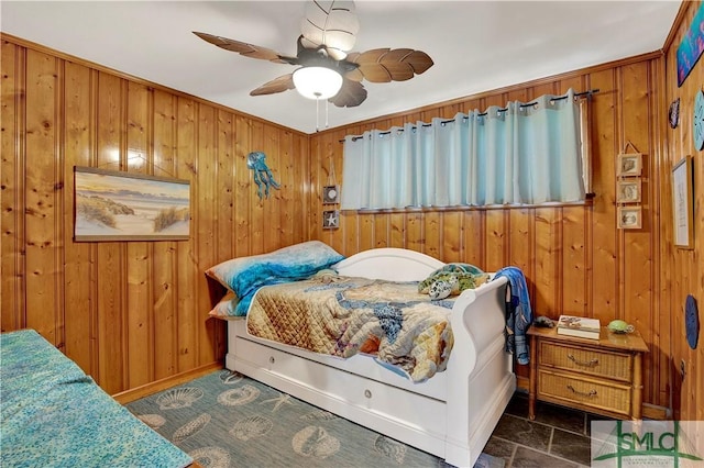 bedroom featuring a ceiling fan and wooden walls