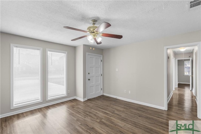 spare room with attic access, dark wood-style flooring, visible vents, and baseboards