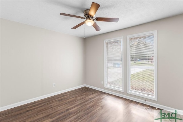 unfurnished room featuring a textured ceiling, dark wood finished floors, a ceiling fan, and baseboards