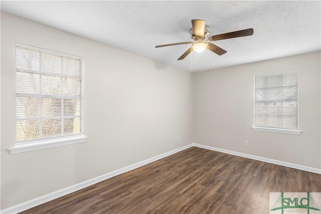 empty room featuring dark wood-type flooring, a textured ceiling, baseboards, and a ceiling fan