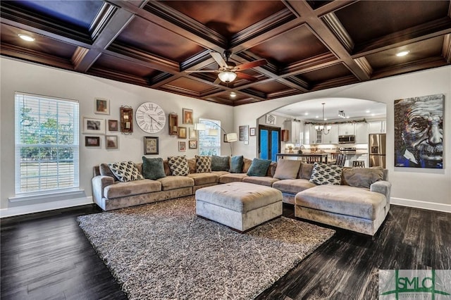 living area with ceiling fan, ornamental molding, and arched walkways