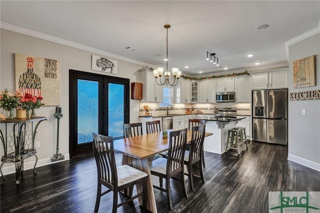 dining area with dark wood-style flooring, visible vents, baseboards, ornamental molding, and an inviting chandelier