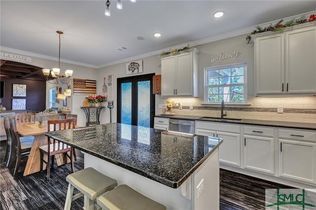 kitchen with ornamental molding, stainless steel dishwasher, a sink, and tasteful backsplash