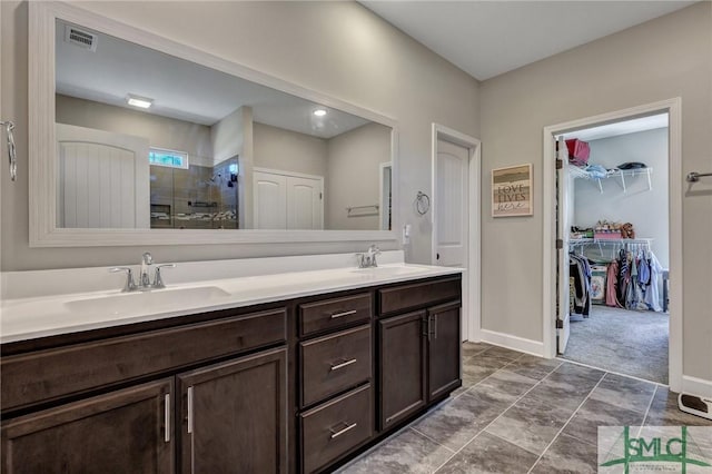 bathroom featuring double vanity, a stall shower, a spacious closet, and a sink