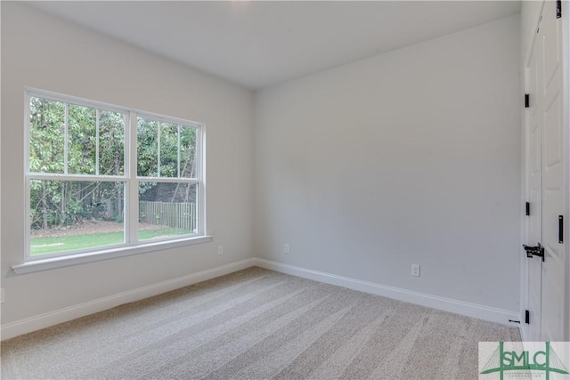 spare room with light carpet and baseboards