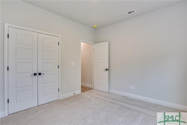 unfurnished bedroom featuring carpet, a closet, visible vents, and baseboards