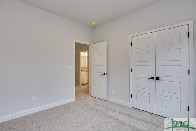 unfurnished bedroom featuring light carpet, baseboards, and a closet