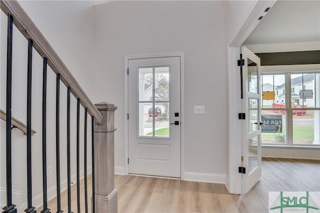 foyer with light wood-style floors, stairway, and baseboards