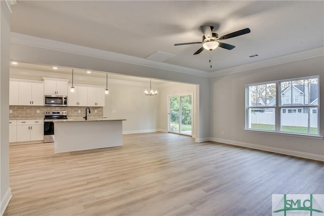 kitchen featuring tasteful backsplash, open floor plan, appliances with stainless steel finishes, light wood finished floors, and crown molding