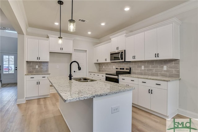 kitchen with stainless steel appliances, ornamental molding, a sink, and a center island with sink