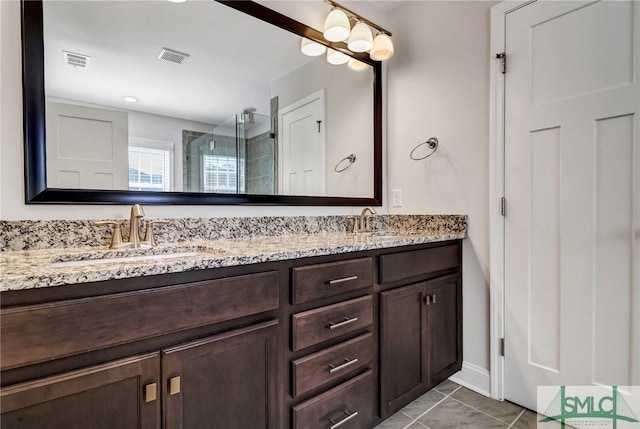 full bath with visible vents, a sink, a shower stall, and double vanity