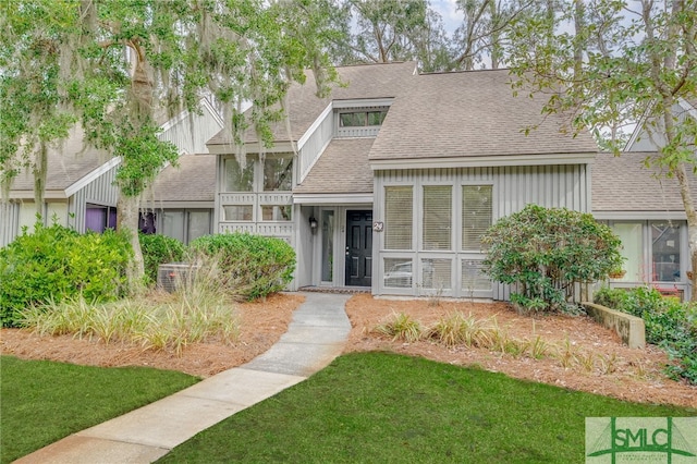 view of front of property with a shingled roof and a front lawn