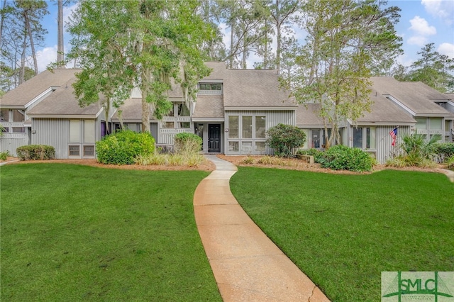 view of front of home with a shingled roof and a front lawn