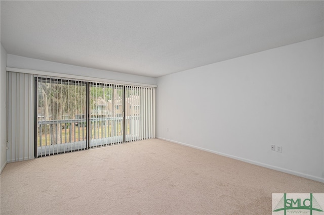 empty room featuring carpet flooring, a textured ceiling, and baseboards