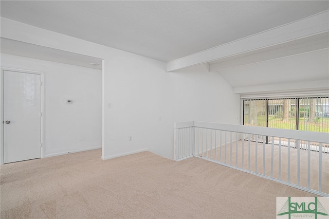 unfurnished room featuring vaulted ceiling with beams, carpet, and a textured ceiling