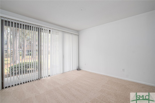 carpeted spare room featuring baseboards