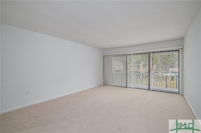 carpeted empty room featuring a textured ceiling and baseboards