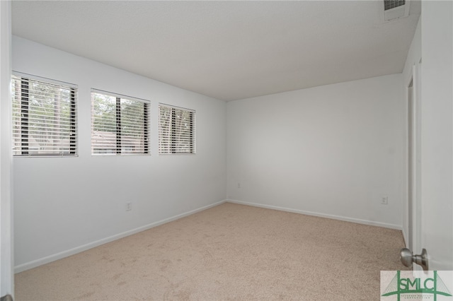 carpeted empty room featuring baseboards and visible vents