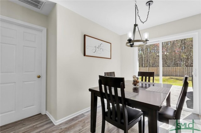 dining space with baseboards, an inviting chandelier, visible vents, and light wood-style floors