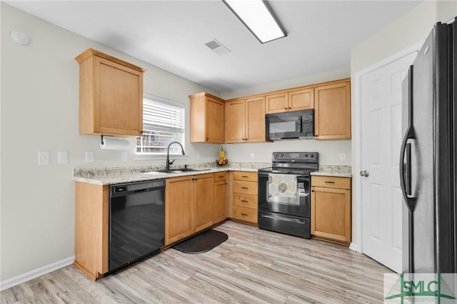 kitchen with baseboards, visible vents, light wood-style floors, black appliances, and a sink