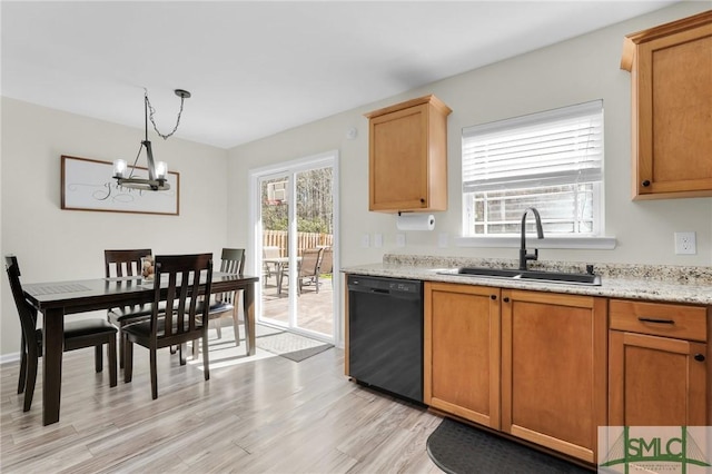 kitchen with pendant lighting, light wood finished floors, a sink, light stone countertops, and dishwasher