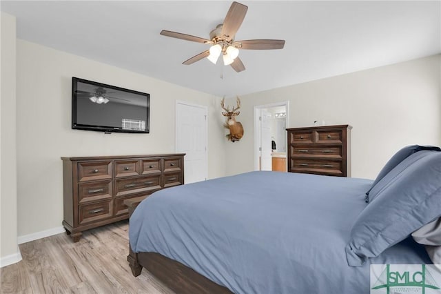 bedroom with light wood finished floors, ensuite bath, a ceiling fan, and baseboards