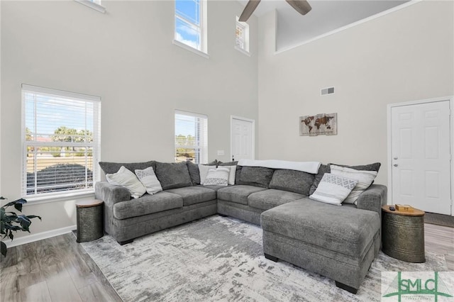 living room featuring ceiling fan, wood finished floors, visible vents, and baseboards