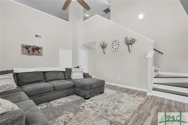 living area with a ceiling fan, visible vents, stairway, and wood finished floors