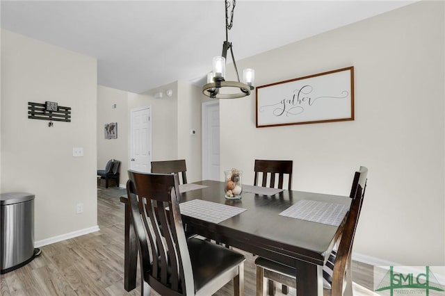 dining space with a chandelier, light wood-type flooring, and baseboards