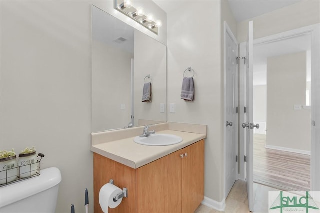 bathroom featuring vanity, toilet, and baseboards