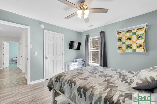 bedroom featuring a ceiling fan, visible vents, baseboards, and wood finished floors