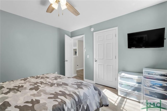 bedroom with ceiling fan, wood finished floors, and baseboards