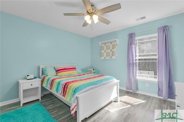 bedroom featuring a ceiling fan, wood finished floors, visible vents, and baseboards