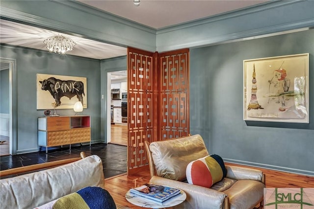 sitting room featuring baseboards, ornamental molding, wood finished floors, and a notable chandelier