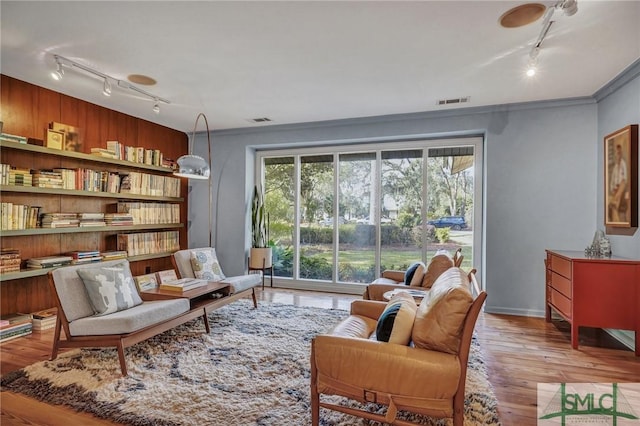 living area with ornamental molding, light wood finished floors, visible vents, and a healthy amount of sunlight