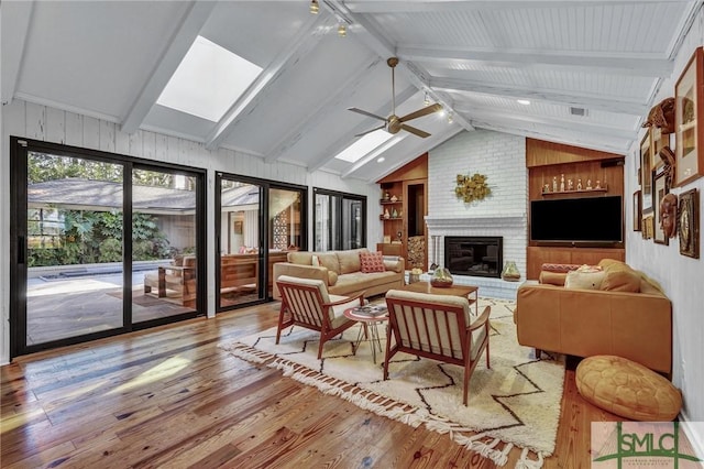 sunroom featuring vaulted ceiling with skylight, a fireplace, and a ceiling fan