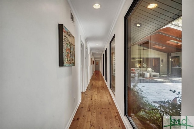 hallway with recessed lighting, visible vents, ornamental molding, wood finished floors, and baseboards