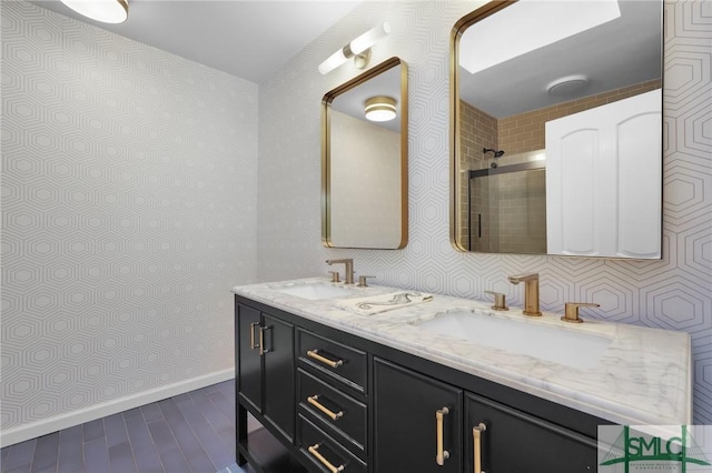 bathroom with baseboards, double vanity, a sink, and wallpapered walls