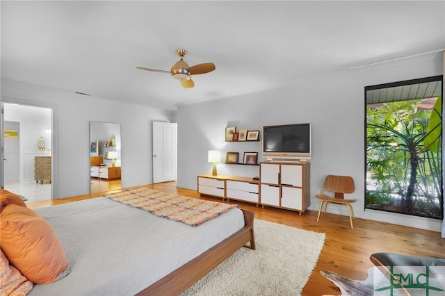 bedroom featuring wood finished floors, a ceiling fan, and connected bathroom