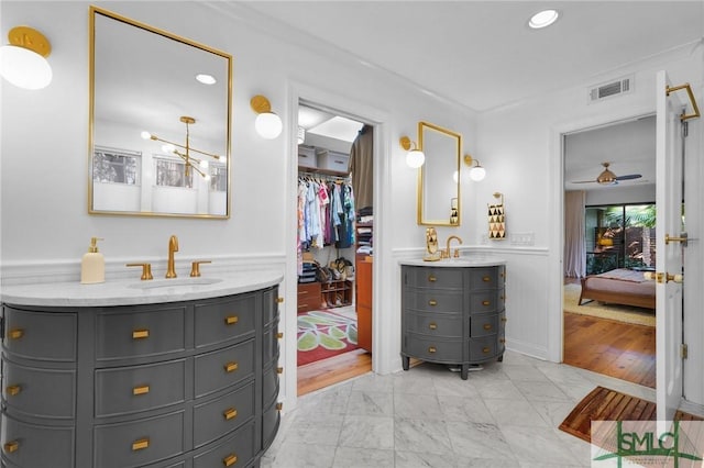 ensuite bathroom with two vanities, a sink, visible vents, marble finish floor, and ensuite bath