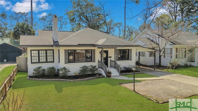 view of front facade with a front yard, brick siding, fence, and a chimney