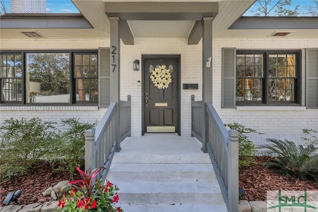 entrance to property with brick siding and visible vents