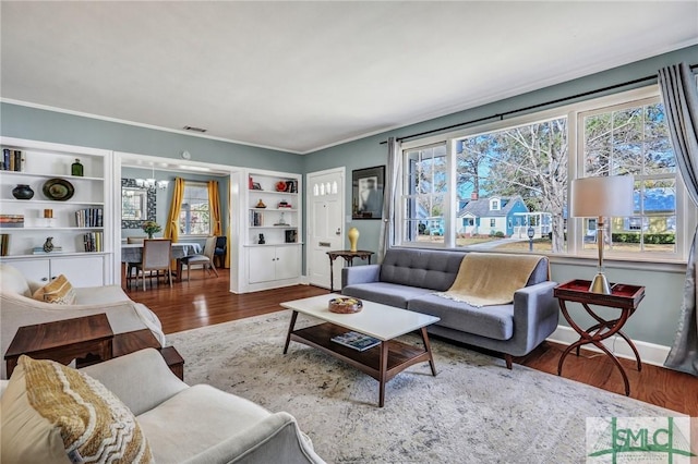 living room with ornamental molding, visible vents, plenty of natural light, and wood finished floors