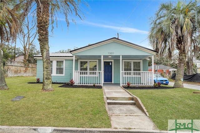 bungalow with covered porch, metal roof, and a front lawn