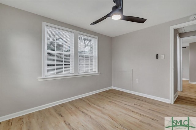 spare room with ceiling fan, wood finished floors, attic access, and baseboards