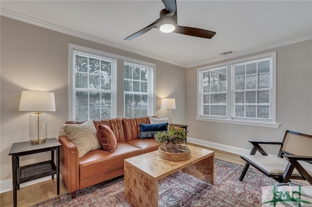 living area with visible vents, ornamental molding, ceiling fan, wood finished floors, and baseboards