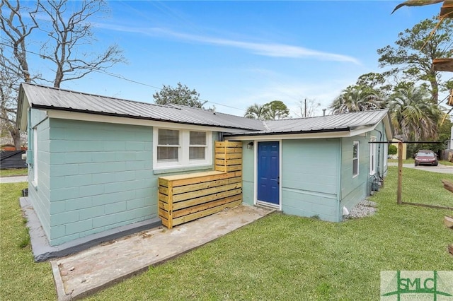 back of property with metal roof, a lawn, and an outdoor structure