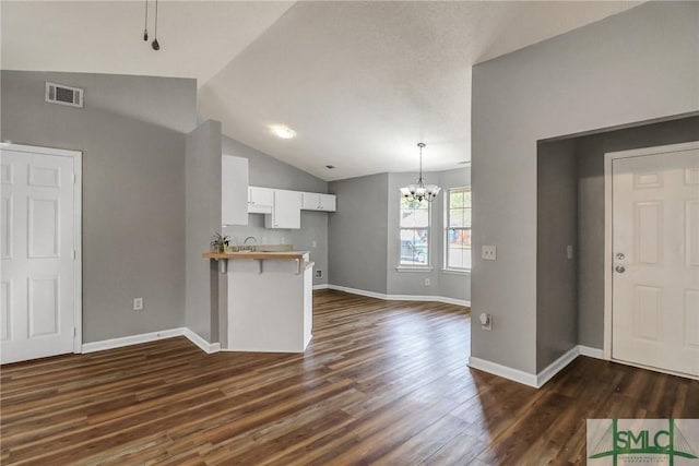 kitchen with a peninsula, dark wood-type flooring, visible vents, and white cabinetry