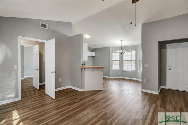 unfurnished living room featuring lofted ceiling, dark wood-style floors, visible vents, and a notable chandelier