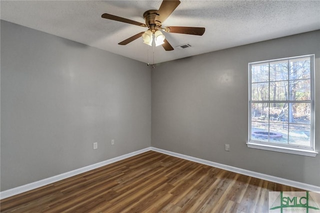 spare room with dark wood-type flooring, visible vents, a textured ceiling, and baseboards